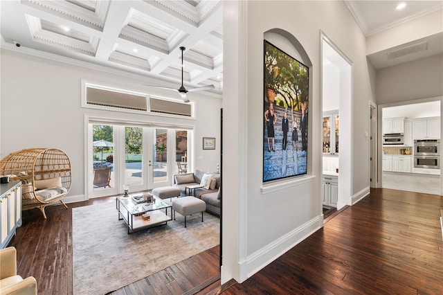 living room featuring a towering ceiling, dark wood-style floors, coffered ceiling, and crown molding