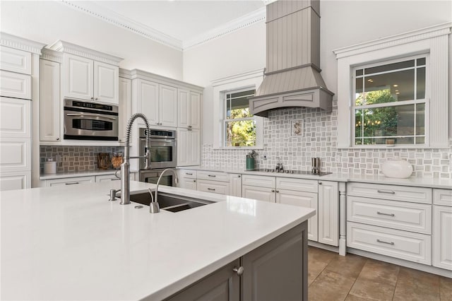 kitchen with backsplash, black electric cooktop, and custom range hood