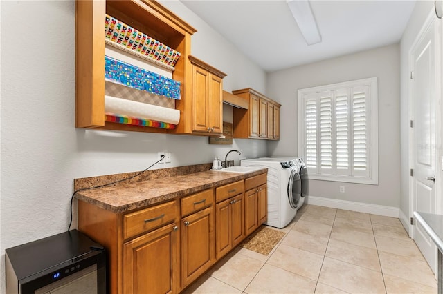 laundry room with baseboards, light tile patterned flooring, independent washer and dryer, and a sink