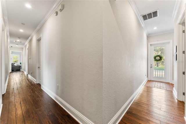 hallway featuring dark wood-type flooring, plenty of natural light, visible vents, and crown molding