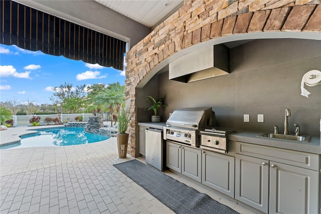 view of patio with an outdoor kitchen, area for grilling, a sink, fence, and a fenced in pool