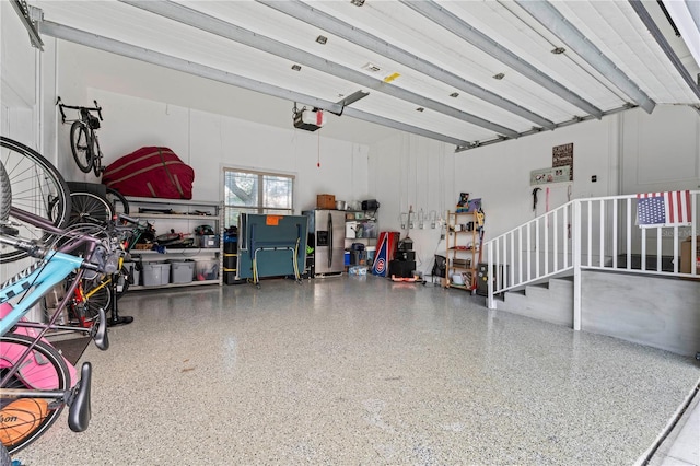 garage with stainless steel refrigerator with ice dispenser and a garage door opener