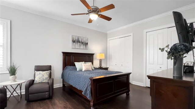 bedroom featuring crown molding, baseboards, dark wood-type flooring, and two closets