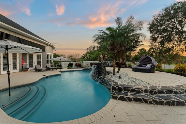 pool at dusk with a fenced in pool, fence, a patio, and french doors