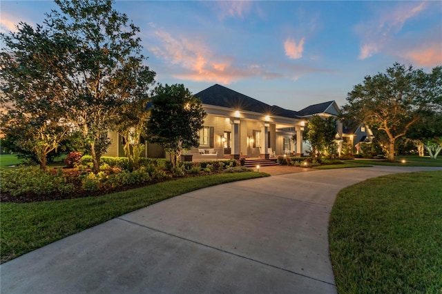 view of front of house with covered porch, a yard, and concrete driveway