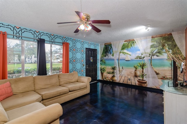 living room featuring finished concrete flooring, wallpapered walls, ceiling fan, and a textured ceiling