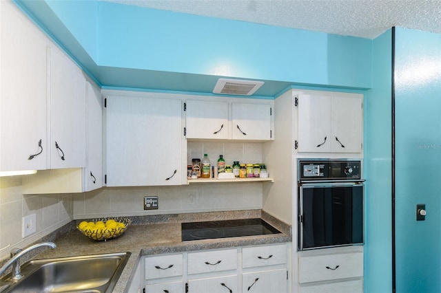 kitchen featuring black appliances, dark countertops, a sink, and white cabinetry