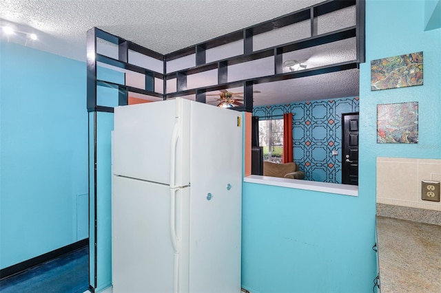 kitchen featuring a textured ceiling, a ceiling fan, freestanding refrigerator, and wallpapered walls