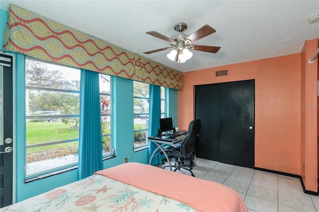 bedroom with a ceiling fan, visible vents, a textured ceiling, and light tile patterned floors