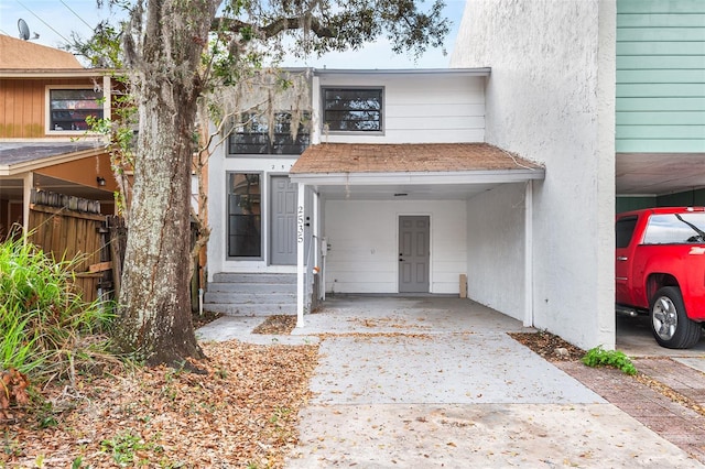 townhome / multi-family property featuring an attached carport, driveway, and stucco siding