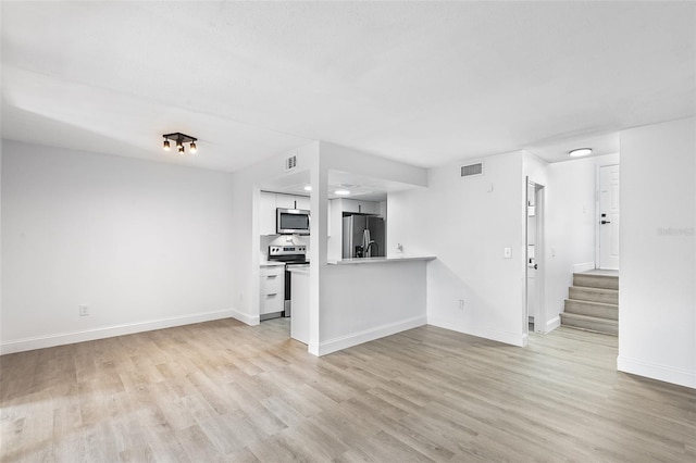 unfurnished living room with light wood-style flooring, stairs, visible vents, and baseboards