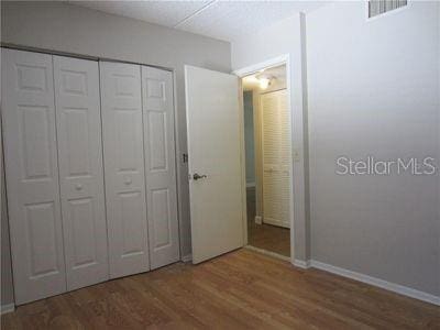 unfurnished bedroom featuring baseboards, a closet, visible vents, and wood finished floors