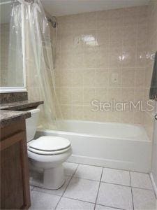 full bath featuring toilet, vanity, shower / bath combination with curtain, and tile patterned floors