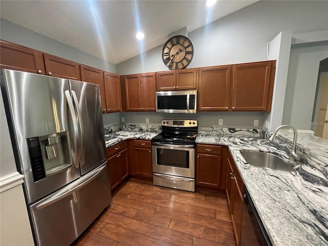 kitchen with stainless steel appliances, a sink, dark wood-style floors, lofted ceiling, and light stone counters