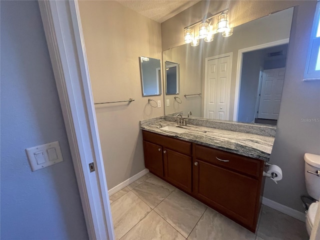 bathroom with toilet, vanity, and baseboards