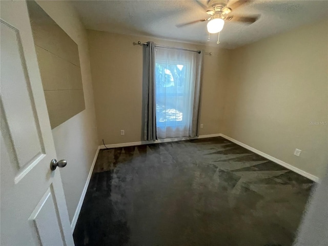 empty room with dark carpet, baseboards, and a ceiling fan