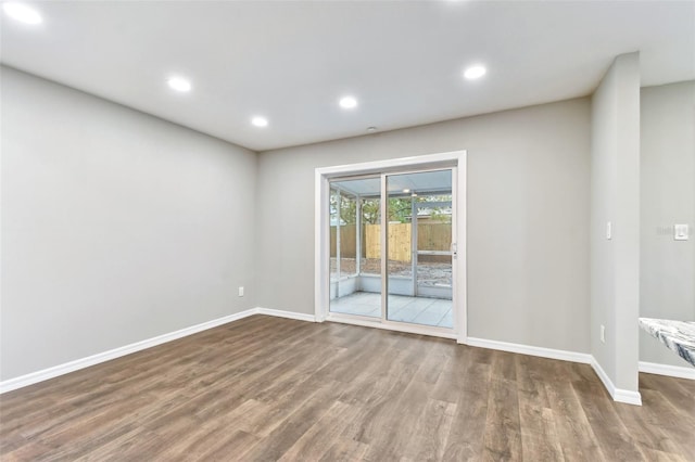 spare room featuring recessed lighting, dark wood-style flooring, and baseboards