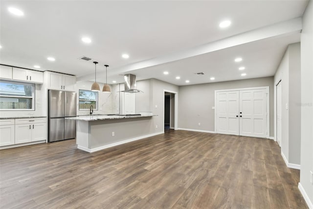 kitchen featuring visible vents, white cabinets, light stone counters, freestanding refrigerator, and pendant lighting