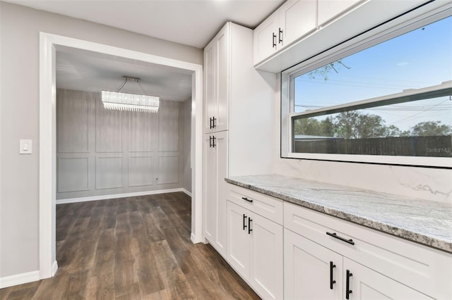 kitchen featuring light stone counters, white cabinetry, baseboards, and dark wood-style floors