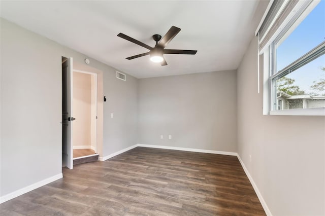 unfurnished room with a ceiling fan, dark wood-style flooring, visible vents, and baseboards