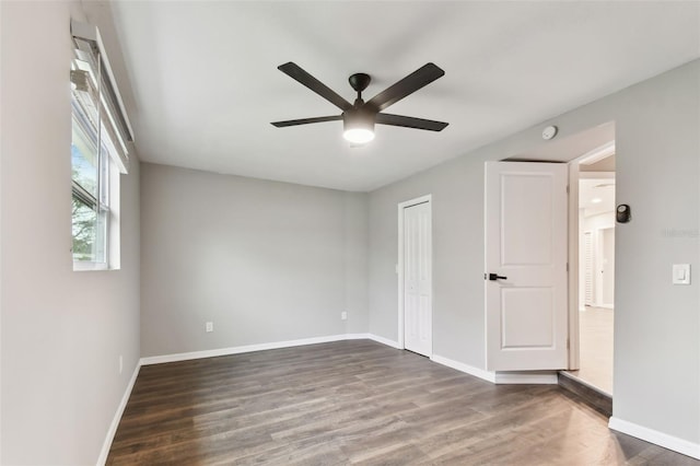 unfurnished bedroom featuring dark wood-style flooring, a closet, a ceiling fan, and baseboards