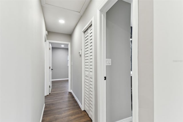 corridor featuring dark wood-style flooring and baseboards