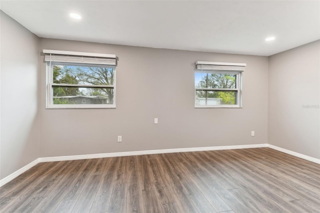 empty room with recessed lighting, wood finished floors, and baseboards