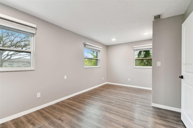 empty room with baseboards, dark wood-type flooring, and recessed lighting