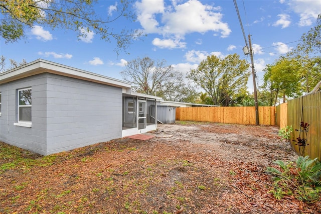 back of property featuring a fenced backyard and a sunroom