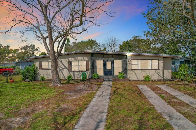 mid-century inspired home featuring a yard, fence, and stucco siding