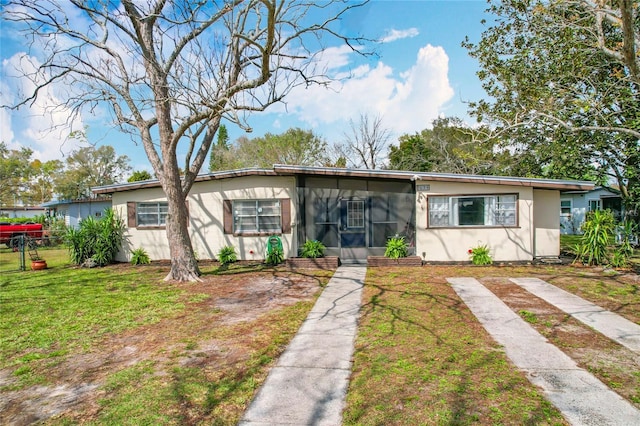 view of front of home featuring a front lawn, fence, a sunroom, and stucco siding