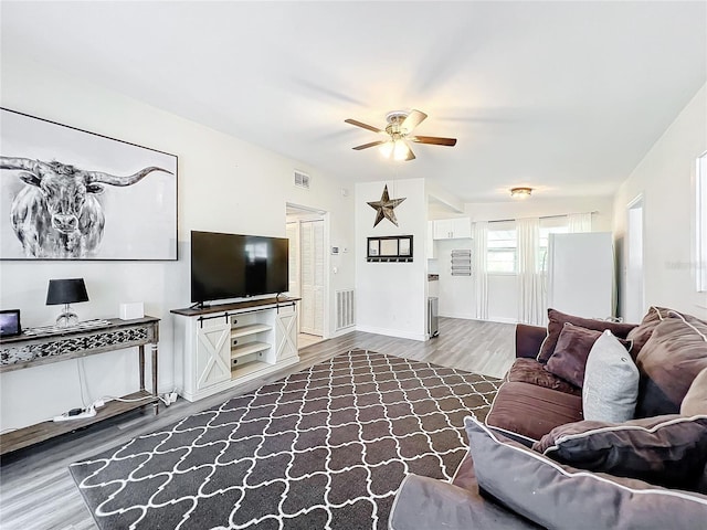 living area with baseboards, ceiling fan, visible vents, and wood finished floors