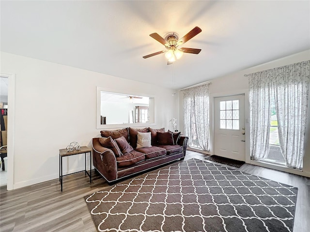 living room with ceiling fan, baseboards, and wood finished floors