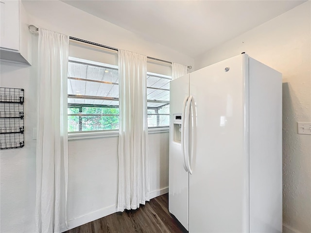 kitchen with white refrigerator with ice dispenser, baseboards, dark wood-style flooring, and white cabinetry