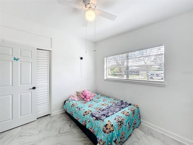 bedroom featuring a ceiling fan, marble finish floor, and baseboards