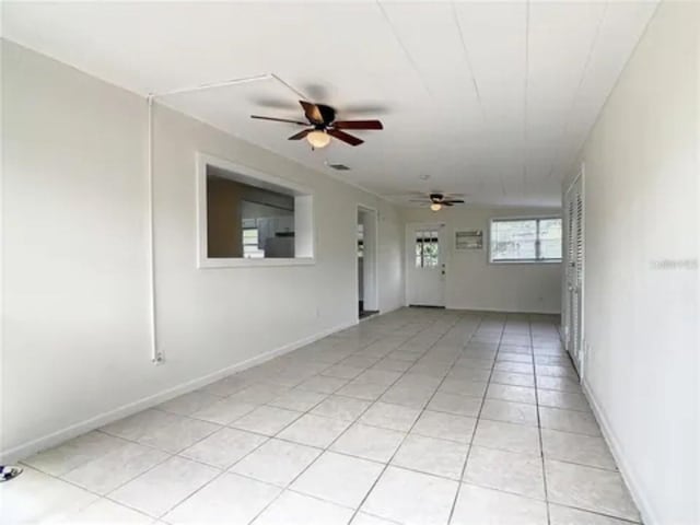 unfurnished room with light tile patterned floors, ceiling fan, and baseboards