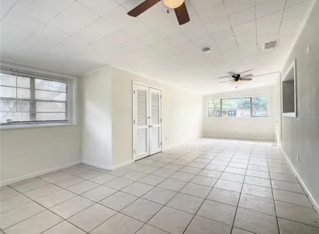 unfurnished room with tile patterned flooring, visible vents, ceiling fan, and baseboards