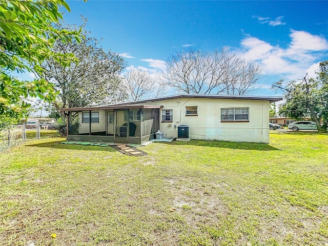 rear view of property with a sunroom, fence, central AC unit, and a yard