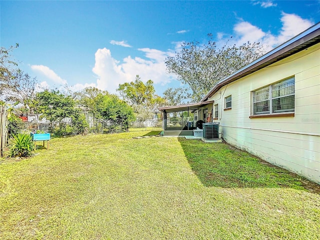 view of yard featuring a sunroom, a fenced backyard, and central AC