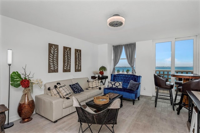 living area featuring light wood-type flooring, baseboards, and a water view