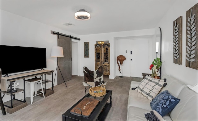 living room featuring a barn door, wood finished floors, and visible vents