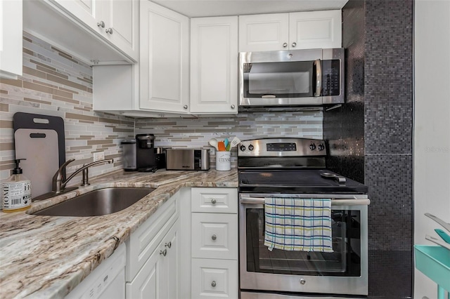 kitchen featuring a sink, light stone counters, backsplash, white cabinetry, and stainless steel appliances