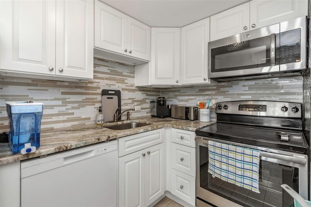 kitchen featuring backsplash, appliances with stainless steel finishes, white cabinets, and a sink