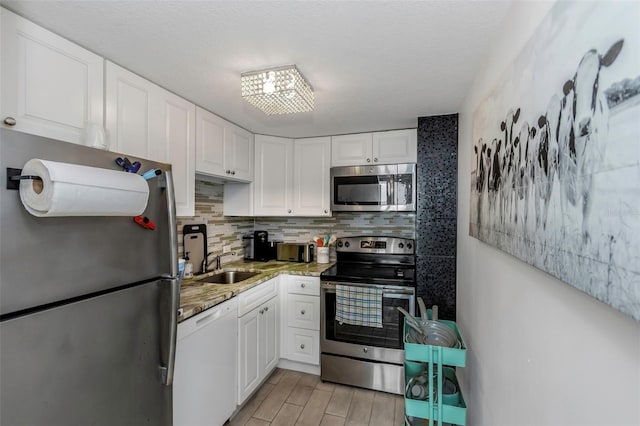 kitchen with a sink, decorative backsplash, white cabinetry, and stainless steel appliances