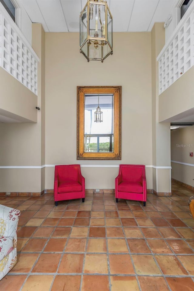 sitting room with tile patterned floors, a high ceiling, and baseboards