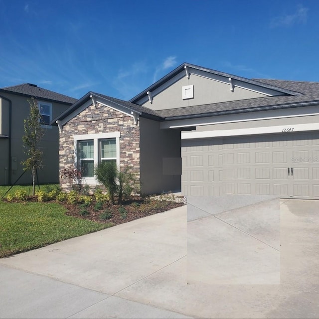 view of front facade with an attached garage, stone siding, a shingled roof, and concrete driveway