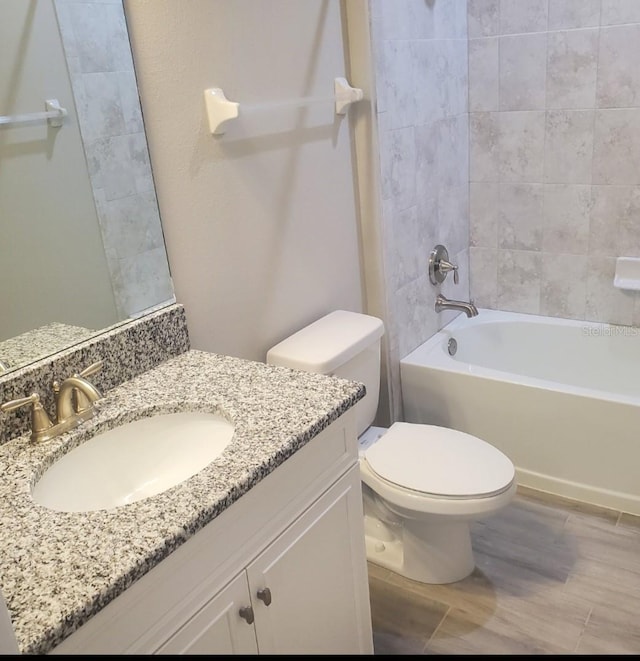 full bath with toilet, bathtub / shower combination, wood finished floors, and vanity