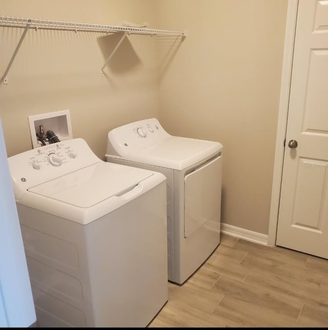 washroom featuring light wood-style floors, washer and dryer, laundry area, and baseboards