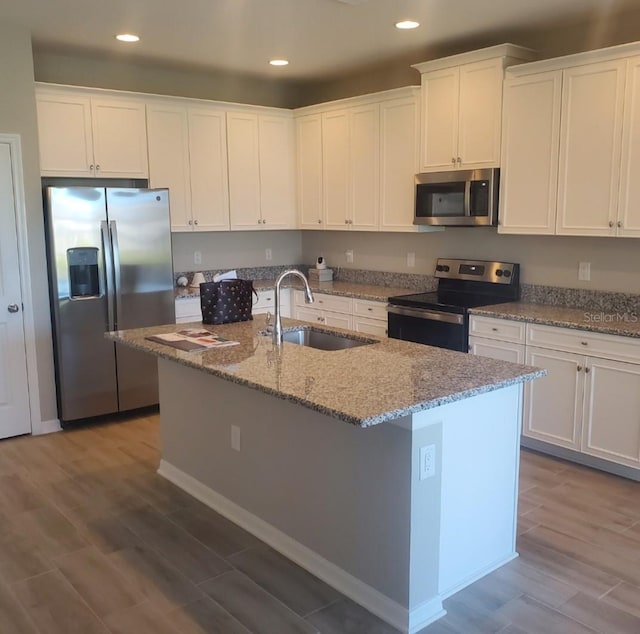 kitchen featuring an island with sink, white cabinetry, appliances with stainless steel finishes, and a sink