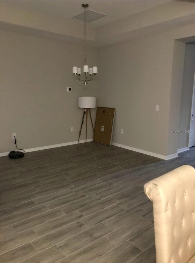 unfurnished dining area featuring wood tiled floor, a notable chandelier, and baseboards